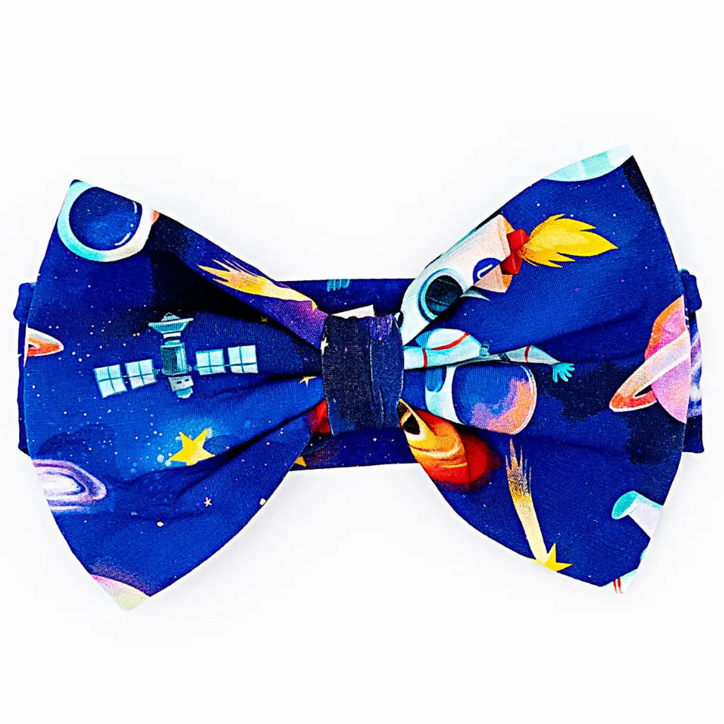 Close-up of a royal blue bow headband printed with astronauts, satellites, planets, and stars on a white background.